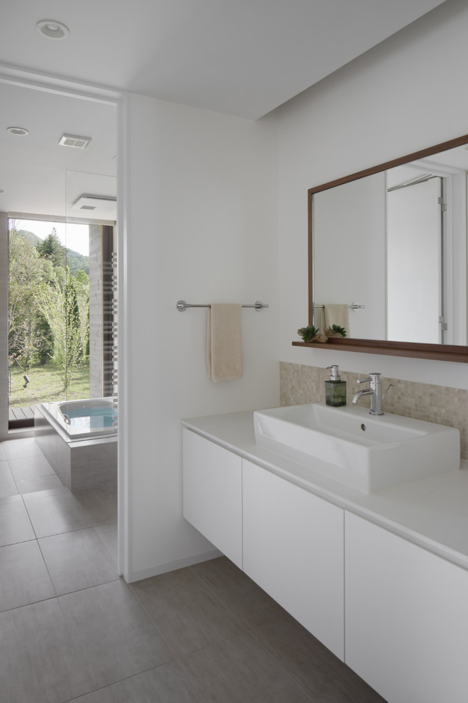 Example of a minimalist gray floor powder room design in Other with flat-panel cabinets, white cabinets, white walls, a vessel sink and white countertops