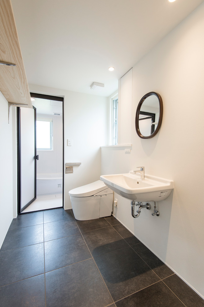 福岡にある北欧スタイルのおしゃれなトイレ・洗面所 (白い洗面カウンター、白い壁、壁付け型シンク、黒い床) の写真