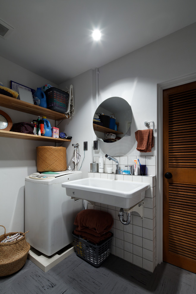 Immagine di un bagno di servizio industriale con pareti bianche, lavabo sospeso e pavimento grigio