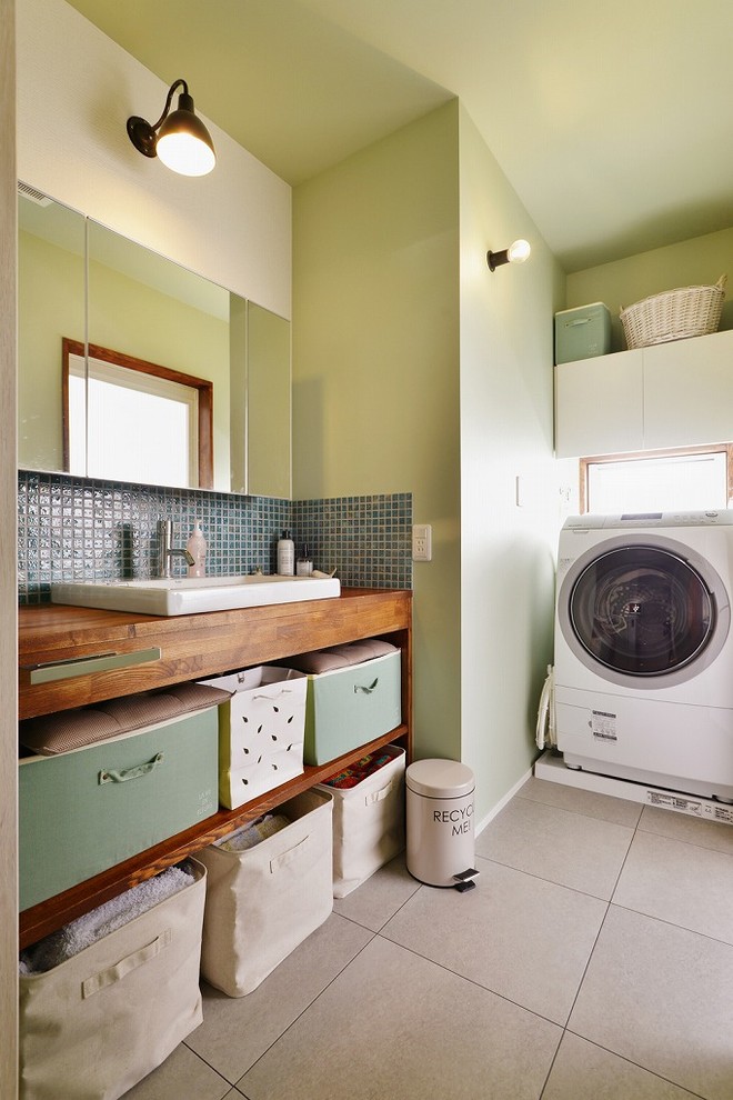 Imagen de aseo nórdico con armarios abiertos, baldosas y/o azulejos verdes, paredes verdes, lavabo encastrado, encimera de madera, suelo gris y encimeras marrones