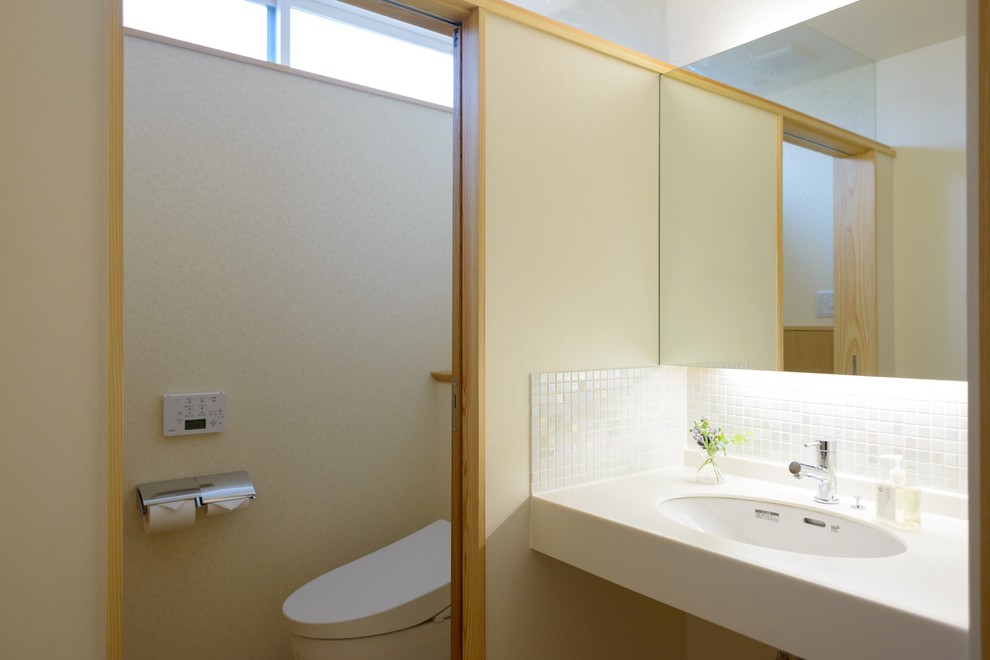Mittelgroße Nordische Gästetoilette mit Toilette mit Aufsatzspülkasten, weißen Fliesen, Mosaikfliesen, weißer Wandfarbe, braunem Holzboden, Unterbauwaschbecken und Mineralwerkstoff-Waschtisch in Sonstige