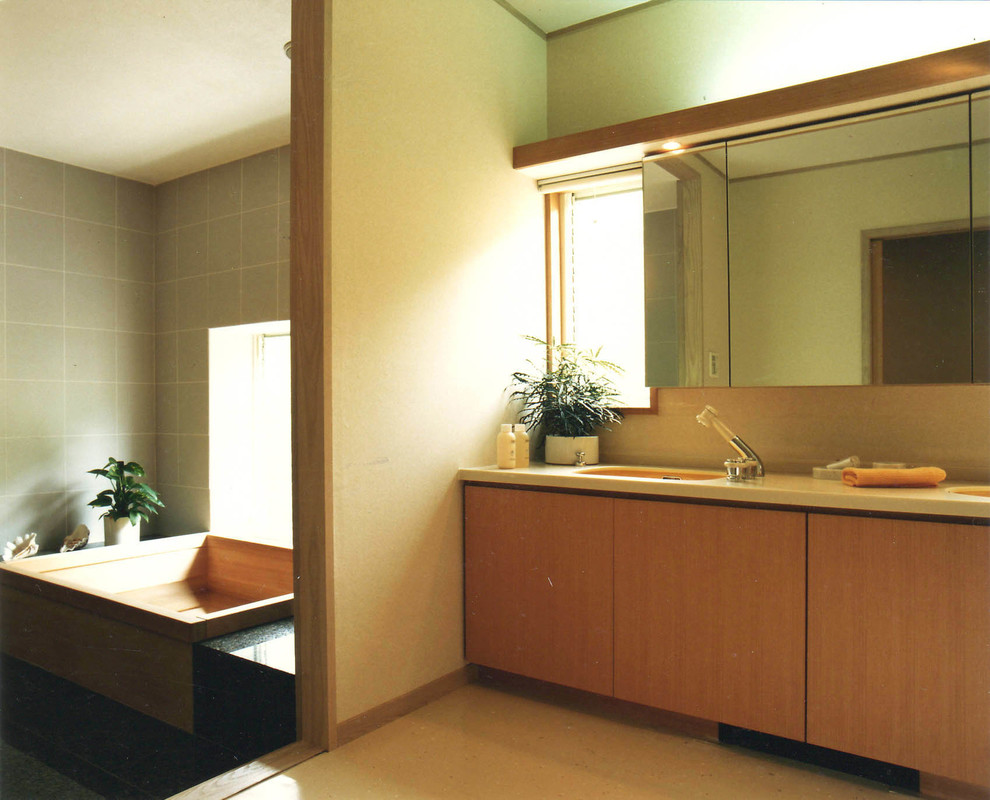 Idee per un bagno di servizio etnico con ante lisce, ante in legno scuro, piastrelle verdi, lavabo integrato, pavimento beige, pareti beige e top in legno