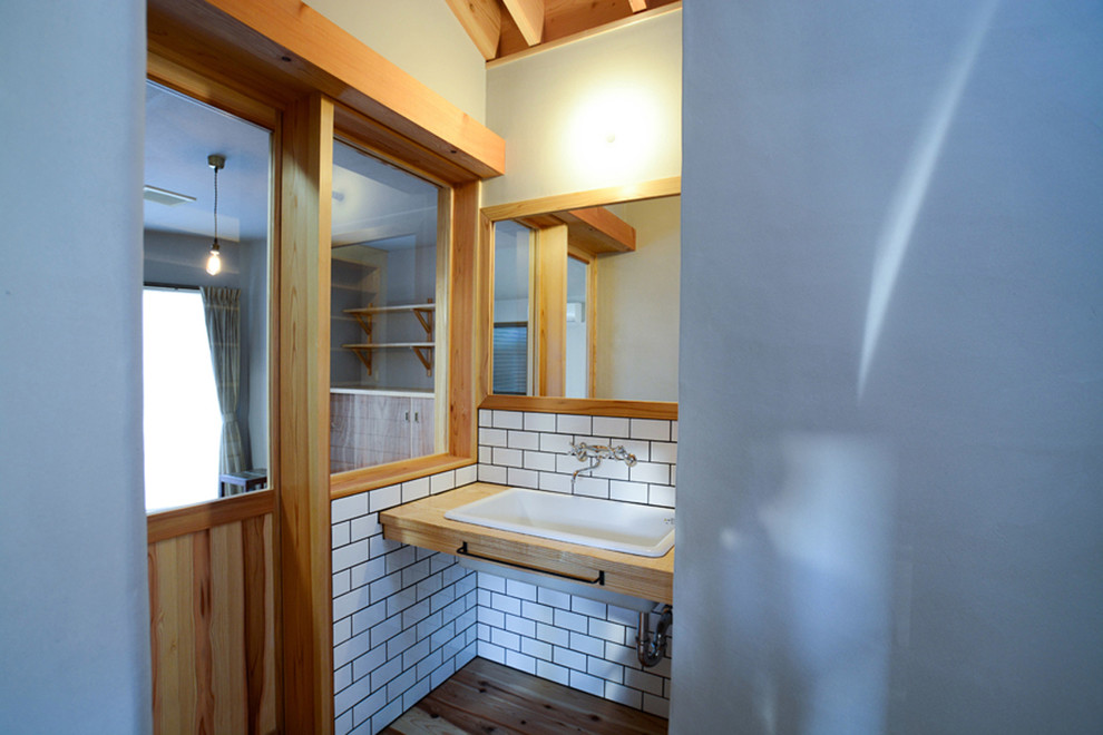 他の地域にある低価格の小さなコンテンポラリースタイルのおしゃれなトイレ・洗面所 (白いタイル、磁器タイル、白い壁、淡色無垢フローリング、アンダーカウンター洗面器、木製洗面台、ベージュの床) の写真