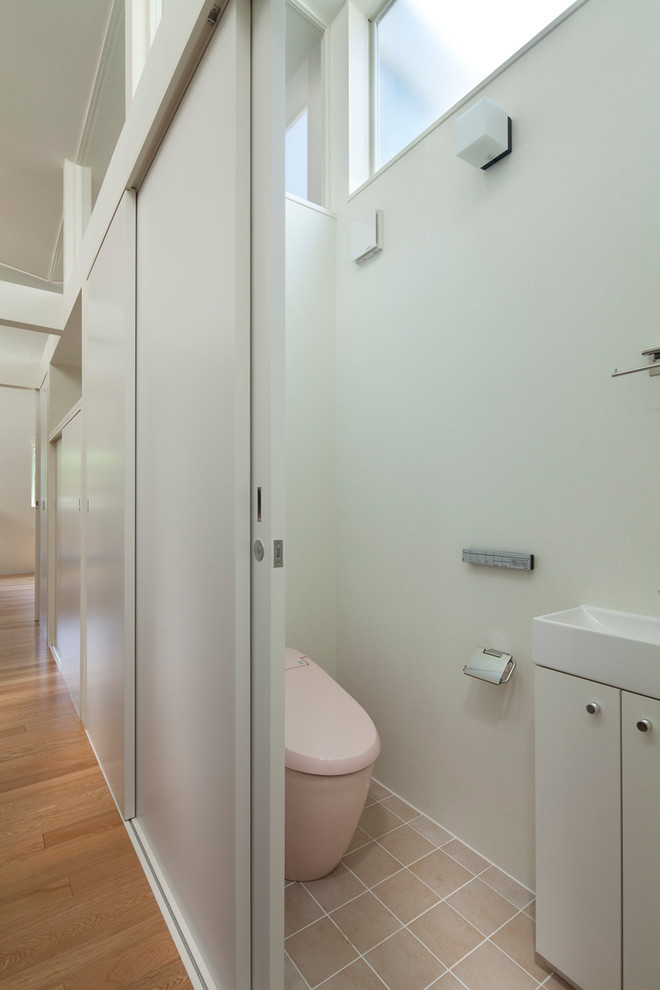 Diseño de aseo contemporáneo con armarios con paneles lisos, puertas de armario blancas, paredes blancas, lavabo integrado y suelo beige