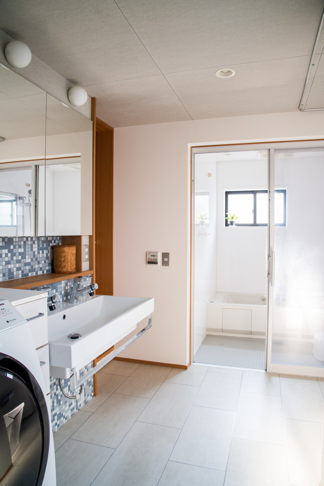 Пример оригинального дизайна: большой туалет в стиле модернизм с унитазом-моноблоком, синей плиткой, плиткой мозаикой, белыми стенами, полом из линолеума, подвесной раковиной и белым полом