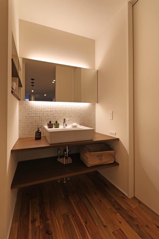 他の地域にある中くらいなラスティックスタイルのおしゃれなトイレ・洗面所 (白い壁、無垢フローリング、ベッセル式洗面器、木製洗面台、茶色い床) の写真