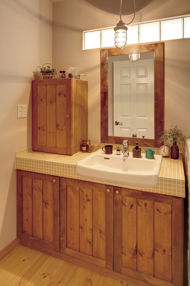 Idées déco pour un WC et toilettes campagne en bois brun avec un placard avec porte à panneau encastré, un mur beige, un sol en bois brun, un plan de toilette en carrelage et un sol marron.
