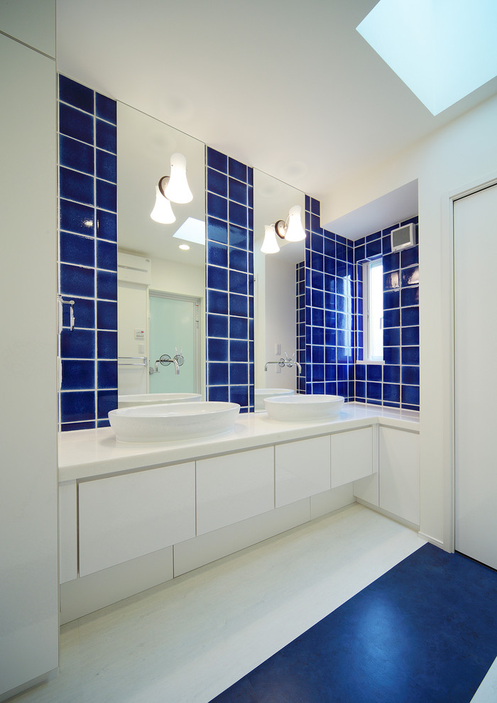 Источник вдохновения для домашнего уюта: туалет среднего размера в современном стиле с плоскими фасадами, белыми фасадами, синей плиткой, керамической плиткой, белыми стенами, полом из винила, консольной раковиной, столешницей из искусственного камня и синим полом