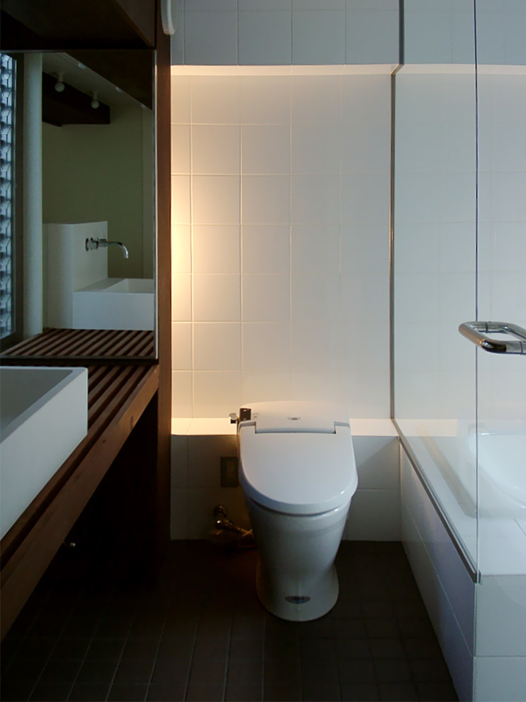 東京23区にあるトランジショナルスタイルのおしゃれなトイレ・洗面所 (セラミックタイル、白い壁、セラミックタイルの床、ベッセル式洗面器、木製洗面台、一体型トイレ	、白いタイル) の写真