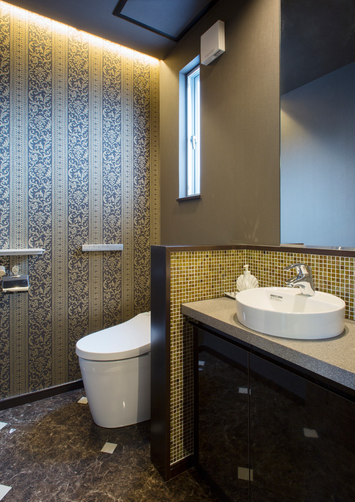 横浜にあるエクレクティックスタイルのおしゃれなトイレ・洗面所 (フラットパネル扉のキャビネット、黒いキャビネット、グレーの壁、ベッセル式洗面器、茶色い床) の写真