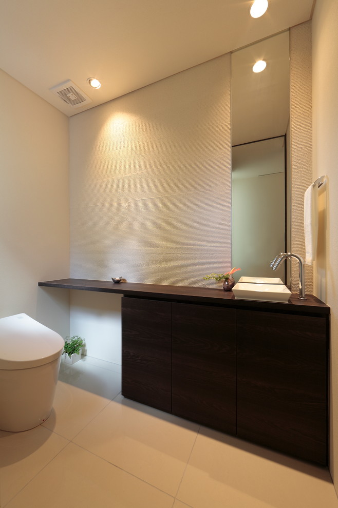 札幌にあるコンテンポラリースタイルのおしゃれなトイレ・洗面所 (白い壁、ベッセル式洗面器、木製洗面台、白い床、ブラウンの洗面カウンター) の写真