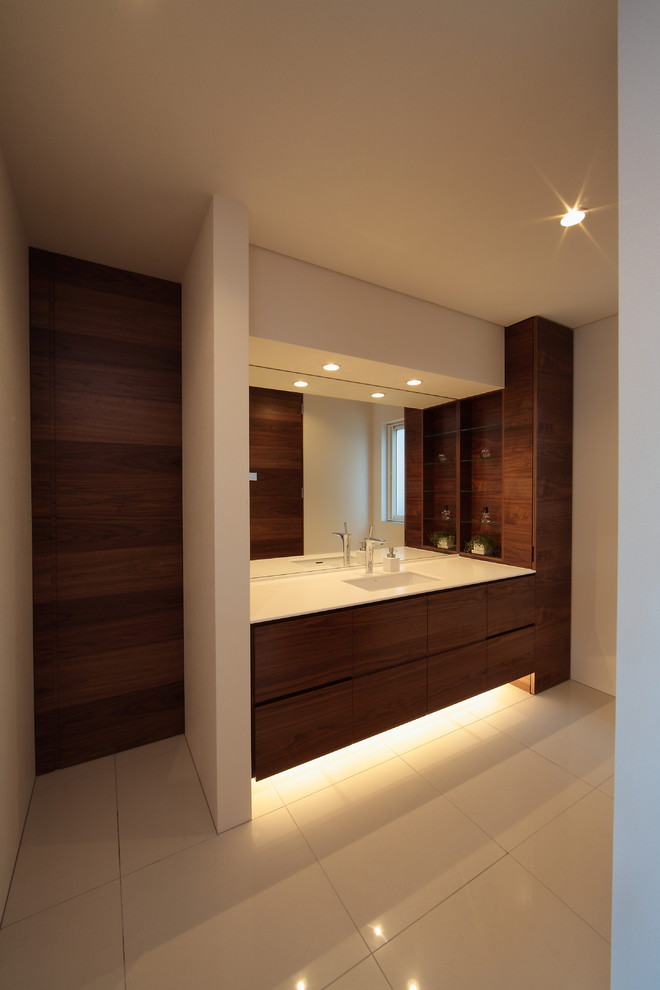 Moderne Gästetoilette mit flächenbündigen Schrankfronten, dunklen Holzschränken, weißer Wandfarbe, integriertem Waschbecken und weißem Boden in Sapporo