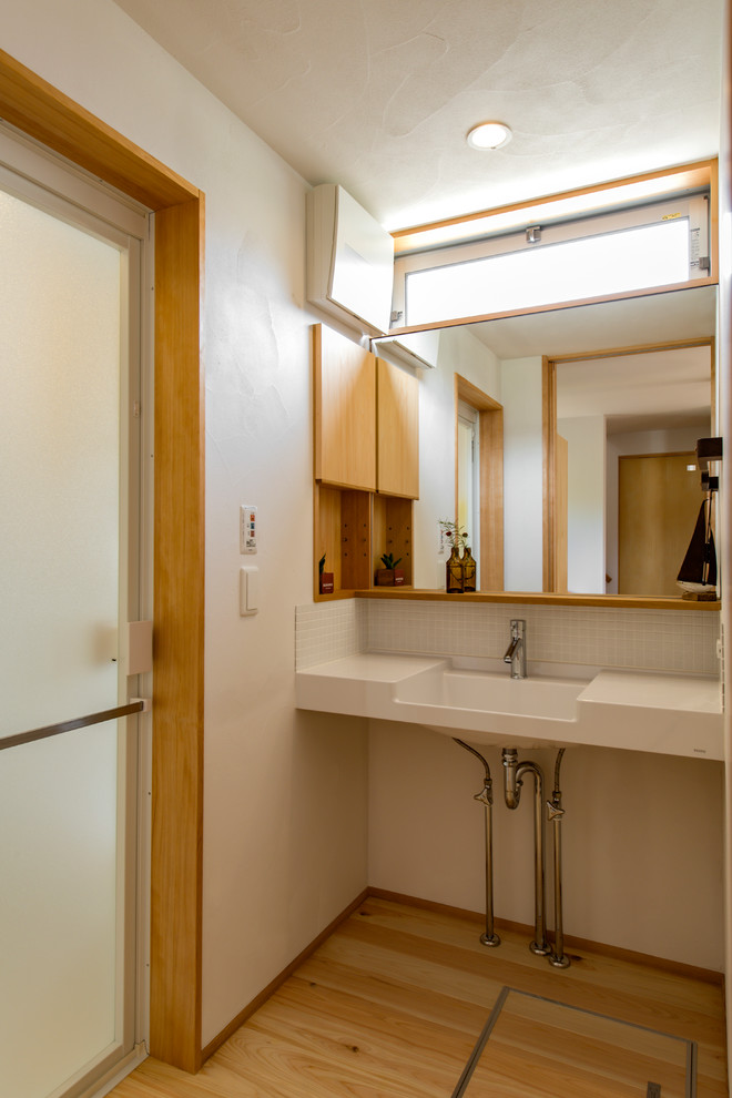 Immagine di un piccolo bagno di servizio nordico con pareti bianche, parquet chiaro, lavabo a consolle, top piastrellato e pavimento beige