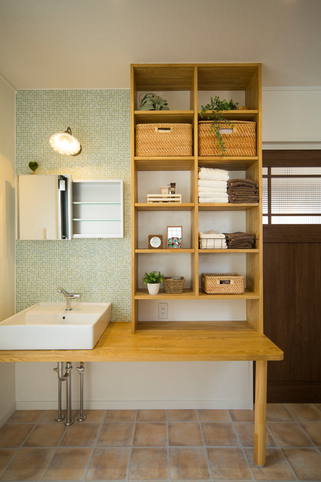 Asiatische Gästetoilette mit grünen Fliesen, Mosaikfliesen, weißer Wandfarbe, Aufsatzwaschbecken, Waschtisch aus Holz, braunem Boden und brauner Waschtischplatte in Sonstige