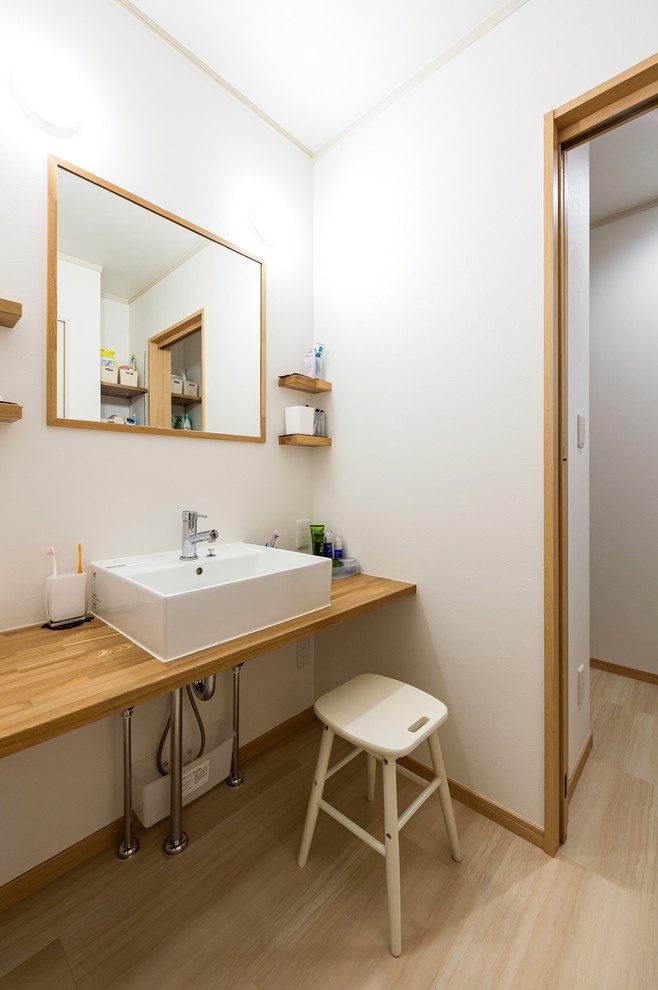 Idéer för att renovera ett lantligt brun brunt toalett, med vita väggar, vinylgolv, ett fristående handfat, beiget golv och skåp i mellenmörkt trä