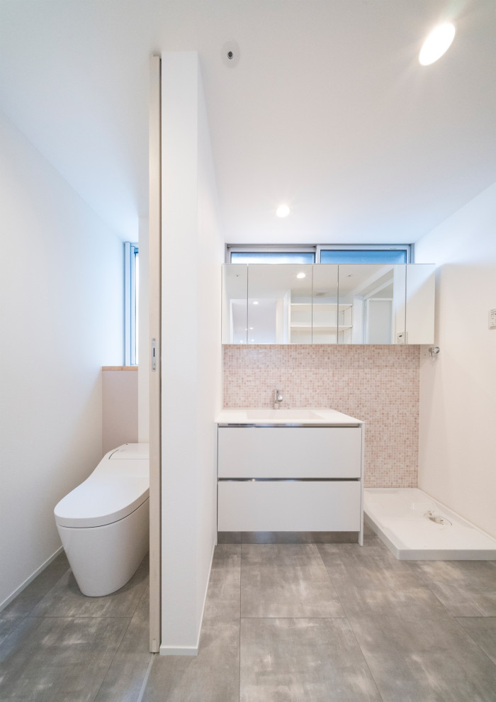 京都にある低価格の小さな北欧スタイルのおしゃれなトイレ・洗面所 (フラットパネル扉のキャビネット、白いキャビネット、一体型トイレ	、ピンクのタイル、モザイクタイル、白い壁、クッションフロア、一体型シンク、人工大理石カウンター、グレーの床、白い洗面カウンター、独立型洗面台、クロスの天井、壁紙) の写真