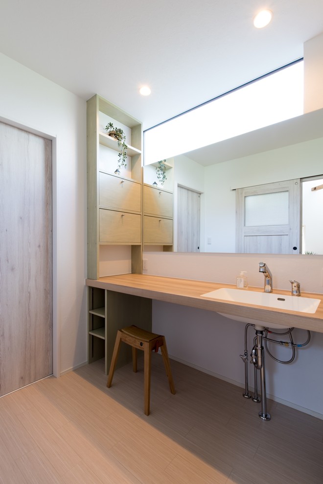 Foto di un bagno di servizio stile rurale di medie dimensioni con ante lisce, ante verdi, pareti bianche, parquet chiaro, lavabo sottopiano, top in legno e top beige