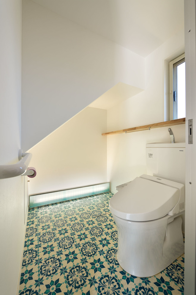 他の地域にあるお手頃価格の小さな北欧スタイルのおしゃれなトイレ・洗面所 (オープンシェルフ、ベージュのキャビネット、一体型トイレ	、ラミネートの床、青い床) の写真