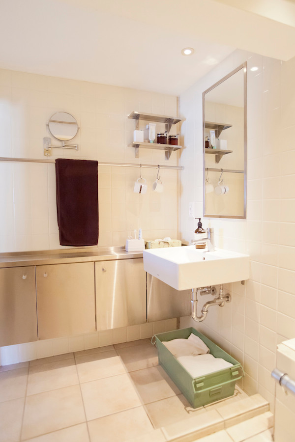 Foto di un bagno di servizio industriale di medie dimensioni con ante lisce, piastrelle bianche, piastrelle di vetro, pareti bianche, lavabo sospeso e top in acciaio inossidabile
