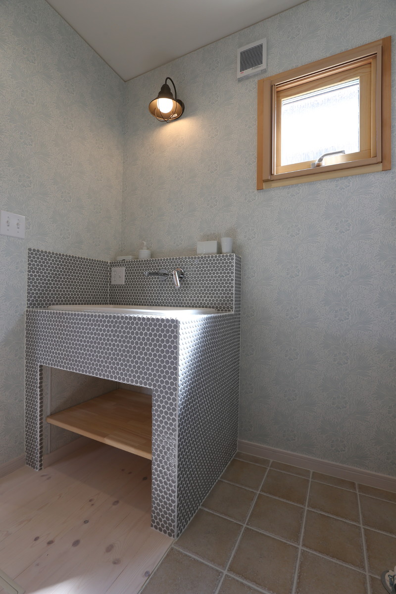 Minimalistisk inredning av ett toalett, med flerfärgade väggar, ljust trägolv, ett nedsänkt handfat, kaklad bänkskiva och vitt golv