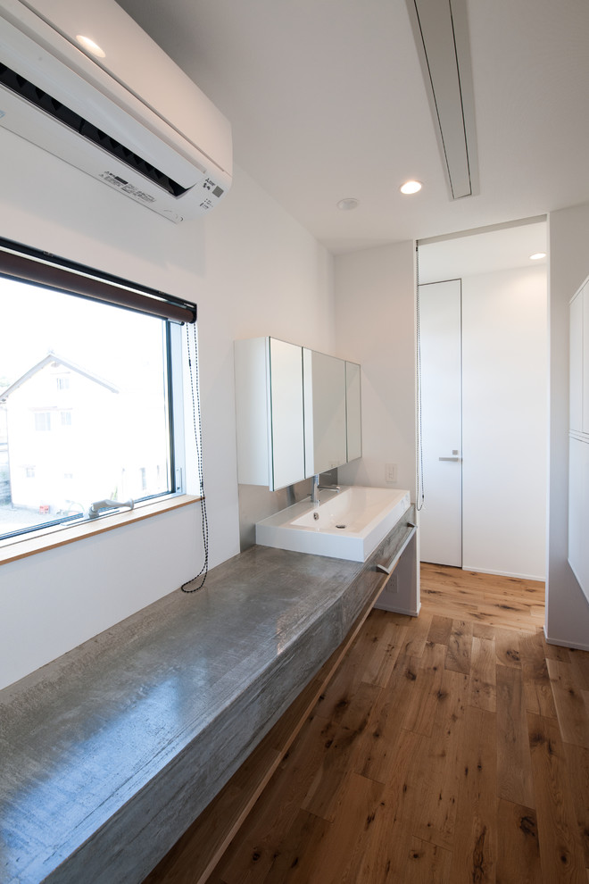 他の地域にあるミッドセンチュリースタイルのおしゃれなトイレ・洗面所 (コンクリートの洗面台、グレーの洗面カウンター) の写真