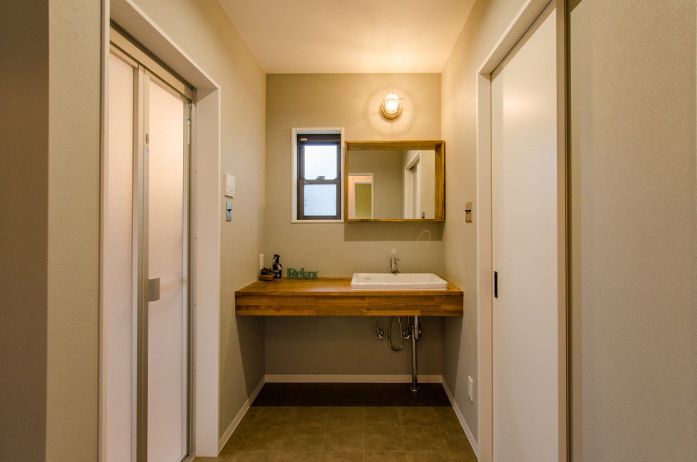 Aménagement d'un petit WC et toilettes industriel en bois brun avec un mur beige, un sol en vinyl, un lavabo posé, un plan de toilette en bois, un sol marron, un plan de toilette marron, meuble-lavabo encastré, un plafond en papier peint et du papier peint.