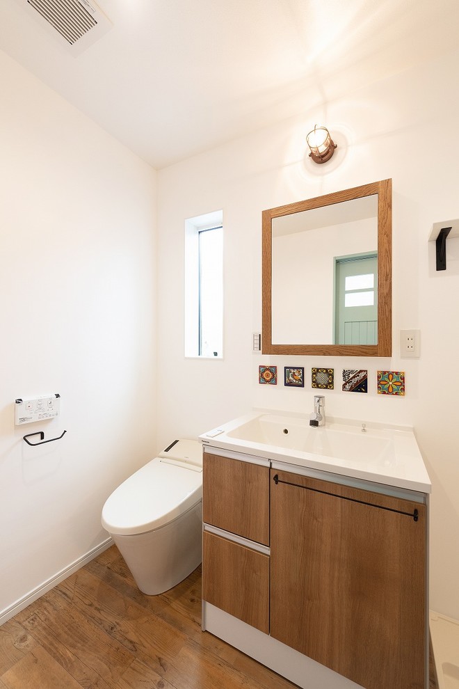Свежая идея для дизайна: туалет в стиле ретро с плоскими фасадами, коричневыми фасадами, белыми стенами, паркетным полом среднего тона, монолитной раковиной и коричневым полом - отличное фото интерьера