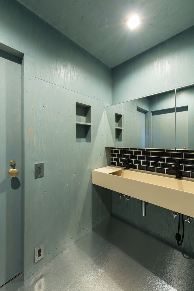Moderne Gästetoilette mit schwarzen Fliesen, blauer Wandfarbe, Wandwaschbecken und blauem Boden in Sonstige