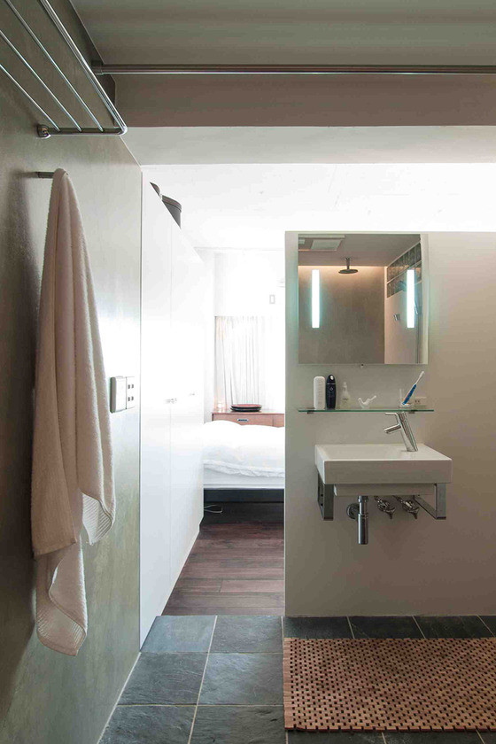 Diseño de aseo moderno pequeño con paredes blancas, suelo de pizarra, lavabo suspendido y encimera de vidrio