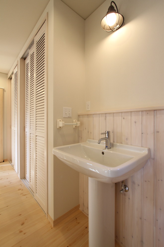 Идея дизайна: туалет в скандинавском стиле с белыми стенами, паркетным полом среднего тона, раковиной с пьедесталом и бежевым полом