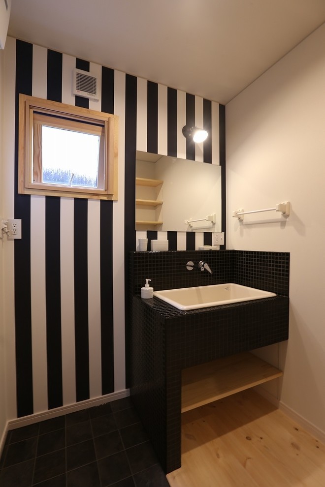 Пример оригинального дизайна: туалет в восточном стиле с открытыми фасадами, черной плиткой, разноцветными стенами, паркетным полом среднего тона, накладной раковиной и столешницей из дерева