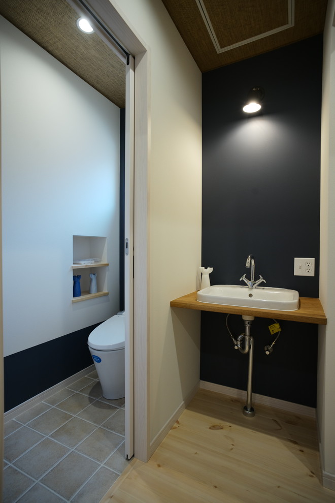 Стильный дизайн: туалет в скандинавском стиле с синими стенами, паркетным полом среднего тона, врезной раковиной, бежевым полом, столешницей из дерева и коричневой столешницей - последний тренд
