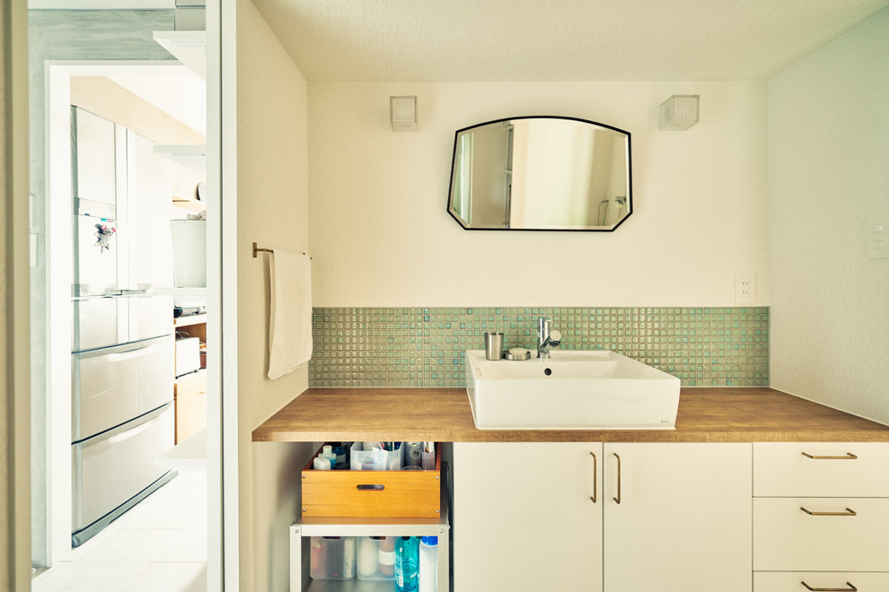 名古屋にあるコンテンポラリースタイルのおしゃれなトイレ・洗面所 (フラットパネル扉のキャビネット、白いキャビネット、緑のタイル、白い壁、ベッセル式洗面器、木製洗面台) の写真