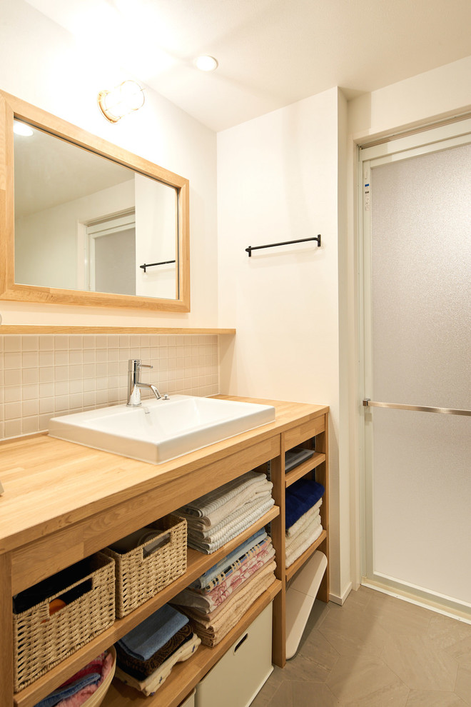 Exempel på ett skandinaviskt toalett, med öppna hyllor, skåp i mellenmörkt trä, vit kakel, porslinskakel, vita väggar, vinylgolv och grått golv
