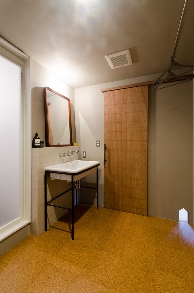 Cette image montre un petit WC et toilettes asiatique avec un carrelage blanc, un mur beige, un sol en liège et une vasque.