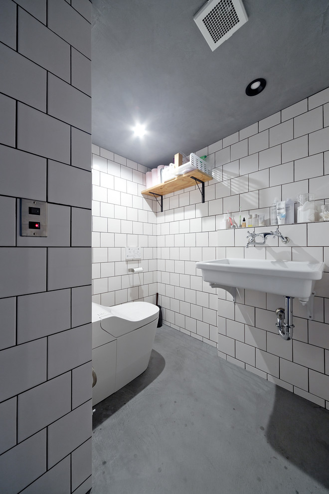 Стильный дизайн: маленький туалет в стиле лофт с белыми стенами, бетонным полом, подвесной раковиной и серым полом для на участке и в саду - последний тренд