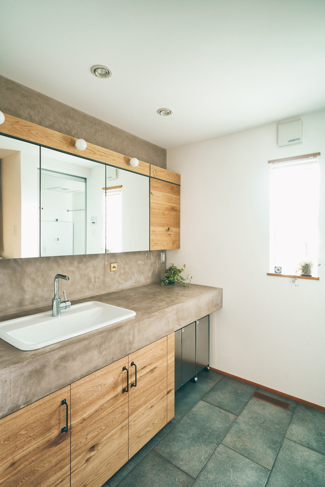Idée de décoration pour un WC et toilettes chalet en bois brun avec un placard à porte plane, un mur blanc, un lavabo posé et un sol vert.