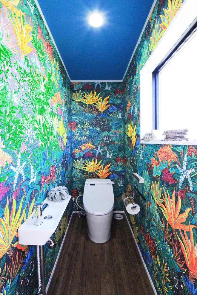他の地域にあるトロピカルスタイルのおしゃれなトイレ・洗面所 (マルチカラーの壁、無垢フローリング、コンソール型シンク、茶色い床) の写真