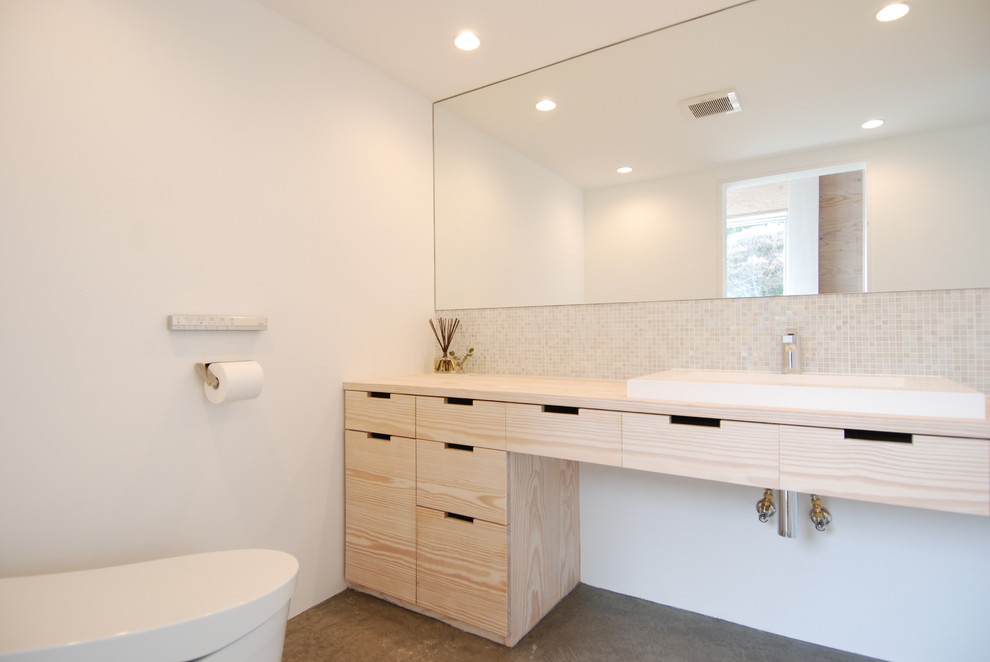 Idées déco pour un WC et toilettes moderne en bois clair avec un placard à porte plane, mosaïque, un mur blanc, sol en béton ciré, un lavabo posé, un plan de toilette en bois et un plan de toilette beige.