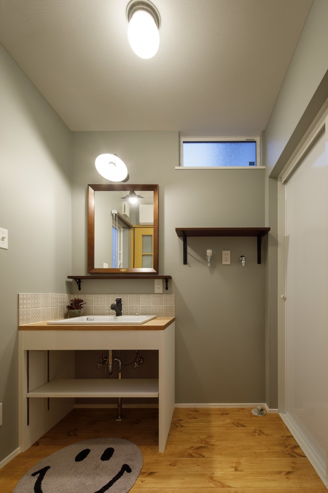 Idee per un bagno di servizio scandinavo con nessun'anta, pareti grigie, pavimento in legno massello medio, lavabo da incasso, top in legno, pavimento marrone e top marrone
