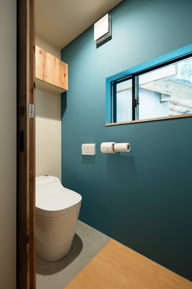 Idées déco pour un petit WC et toilettes asiatique avec WC à poser, un mur bleu et un sol en bois brun.