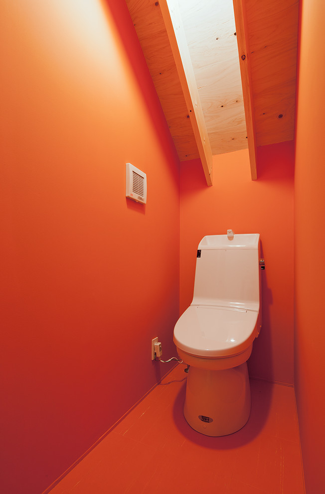 Asiatische Gästetoilette mit rotem Boden, Wandtoilette mit Spülkasten und oranger Wandfarbe in Sonstige