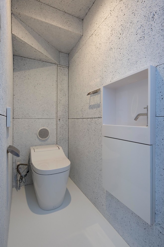 Bild på ett funkis toalett, med släta luckor, vita skåp, vita väggar och vitt golv