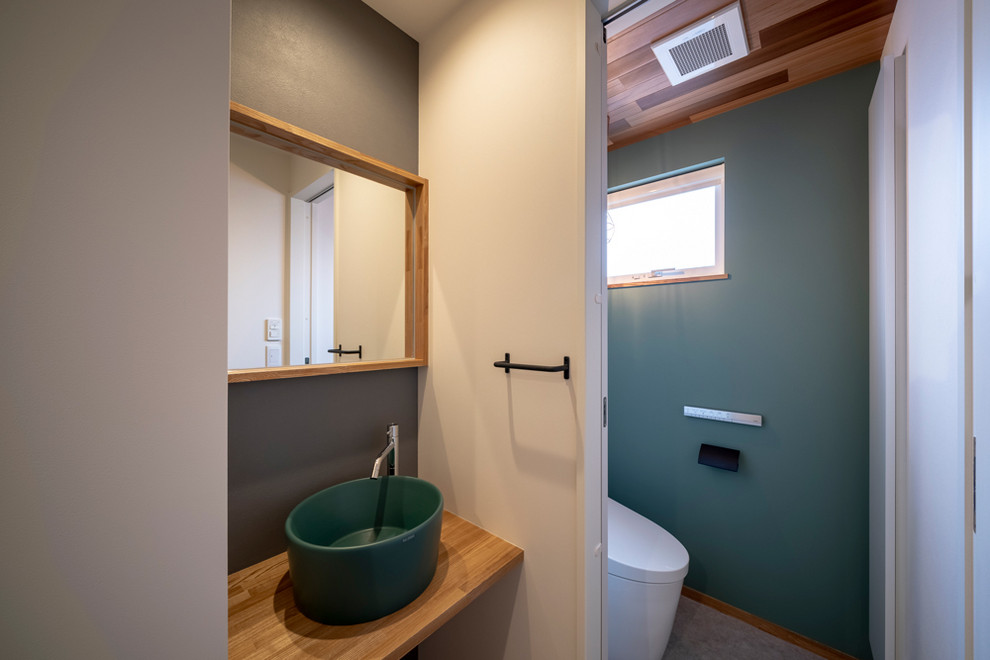 Idee per un bagno di servizio design di medie dimensioni con nessun'anta, WC monopezzo, pareti grigie, pavimento in vinile, lavabo a bacinella, top in legno, pavimento grigio e top marrone