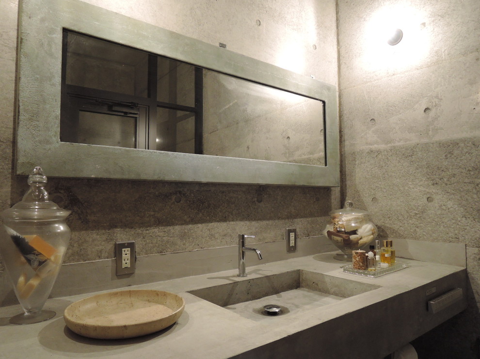Foto på ett industriellt toalett, med öppna hyllor, en toalettstol med hel cisternkåpa, grå väggar, betonggolv, ett integrerad handfat, bänkskiva i betong och grått golv