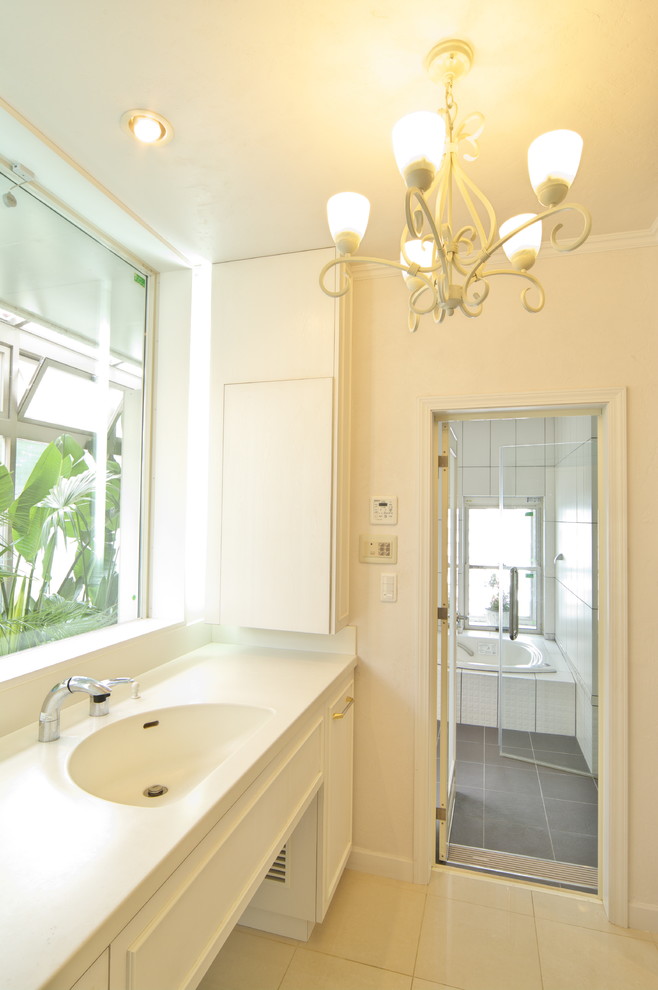 Ispirazione per un bagno di servizio vittoriano con ante con bugna sagomata, ante bianche, pareti bianche, lavabo integrato e pavimento beige