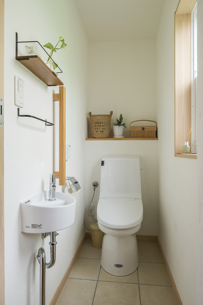 Idées déco pour un WC et toilettes campagne avec WC à poser, un mur blanc, une vasque, un sol blanc et tomettes au sol.