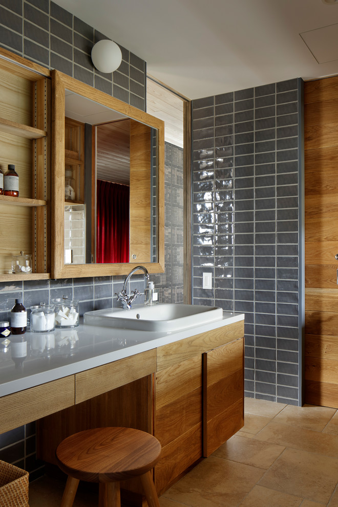 他の地域にある北欧スタイルのおしゃれなトイレ・洗面所 (フラットパネル扉のキャビネット、中間色木目調キャビネット、グレーの壁、オーバーカウンターシンク、ベージュの床) の写真