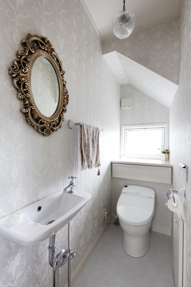 他の地域にあるシャビーシック調のおしゃれなトイレ・洗面所 (グレーの壁、グレーの床、一体型トイレ	、壁付け型シンク) の写真