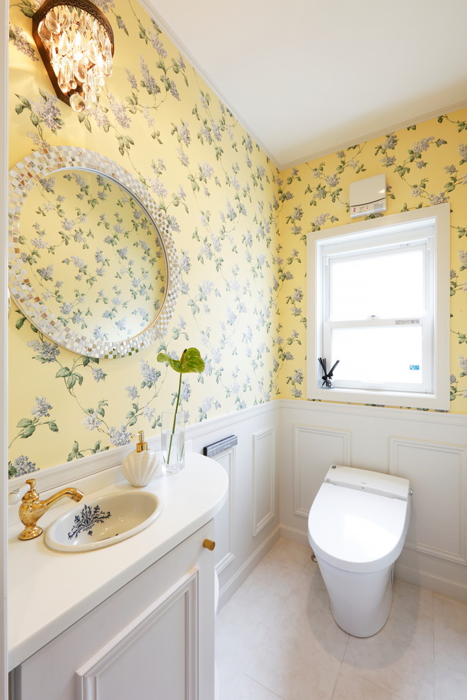 他の地域にあるトラディショナルスタイルのおしゃれなトイレ・洗面所 (落し込みパネル扉のキャビネット、白いキャビネット、黄色い壁、ベージュの床) の写真